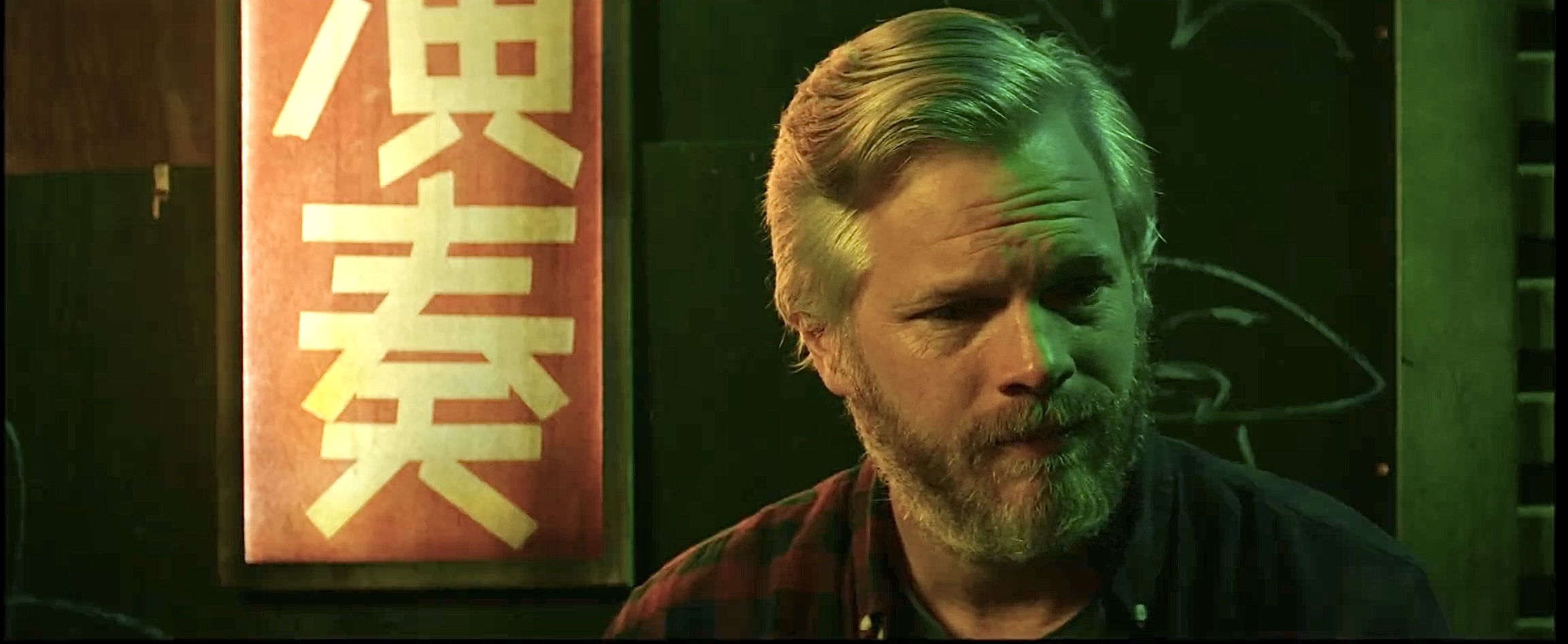 A man in green and amber bar light in a still from Other You