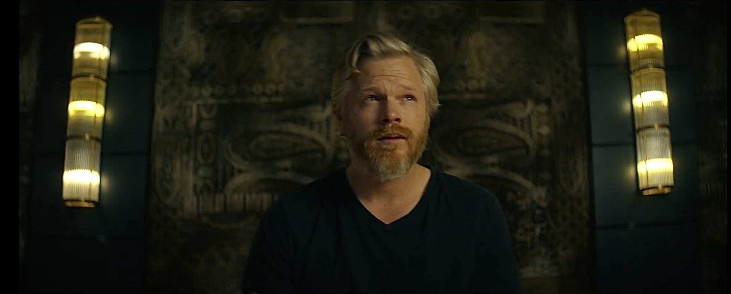 A man standing beside a stone wall and lamps — Other You production still