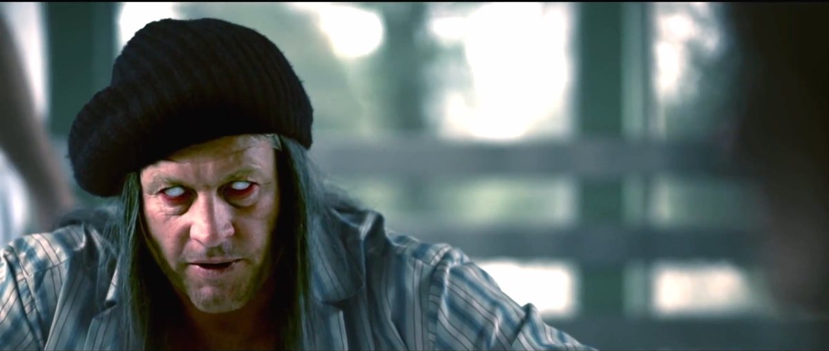 A pale-eyed character in a dark cap — Shadow Wars film still